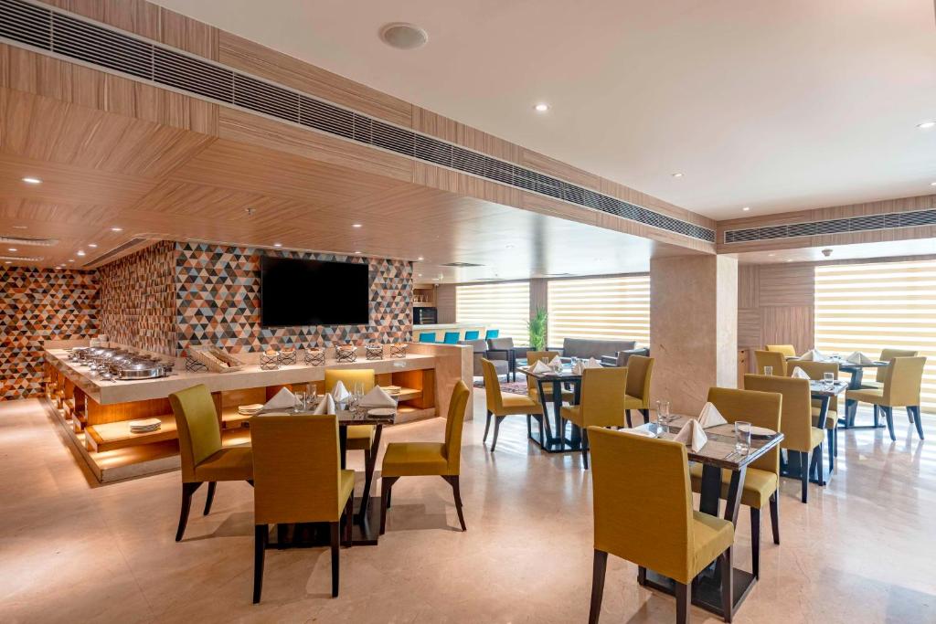 a restaurant with tables and chairs and a flat screen tv at Svelte Delhi, a member of Radisson Individuals in New Delhi
