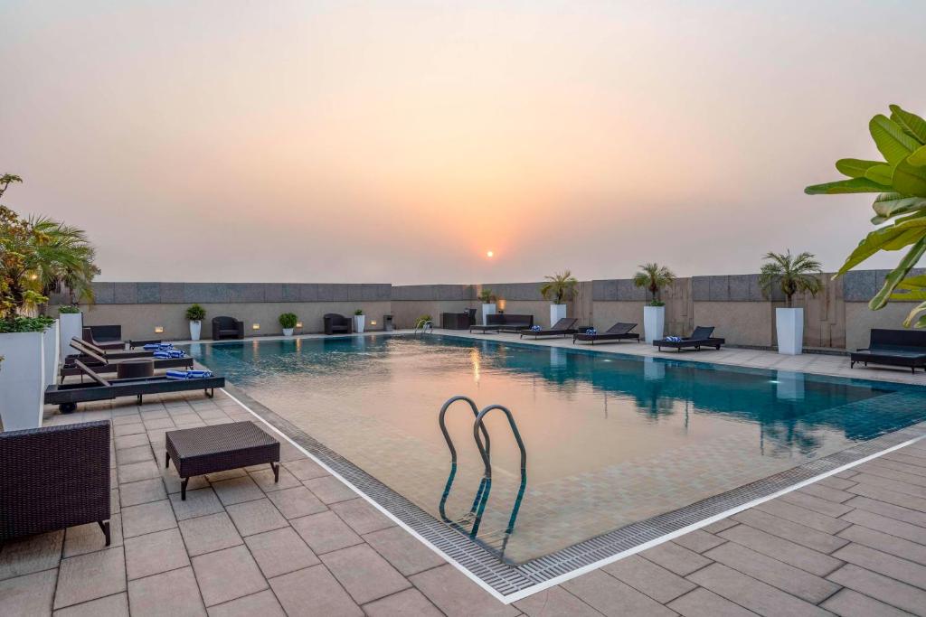 a swimming pool with a sunset in the background at Svelte Delhi, a member of Radisson Individuals in New Delhi