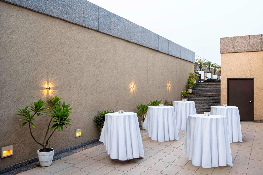 a row of tables with white table cloths in front of a building at Svelte Delhi, a member of Radisson Individuals in New Delhi