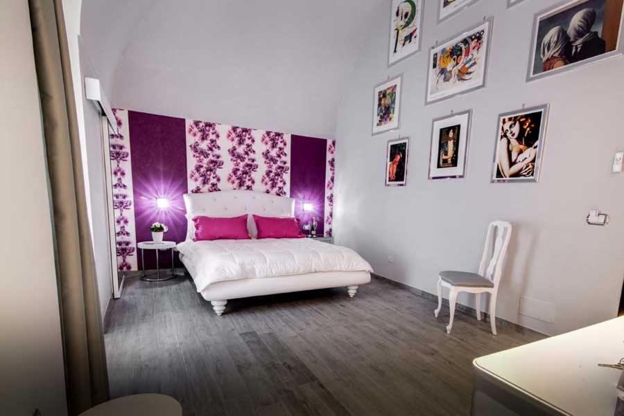 バルレッタにあるMarco Polo B&Bの白いベッドと紫の壁が備わるベッドルーム1室