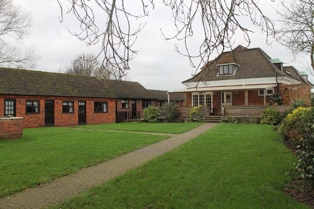 een stenen huis met een grasveld ervoor bij Swan Motel in Beccles