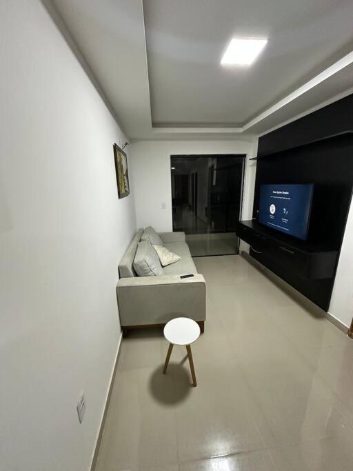 a small living room with a couch and a stool at Apto 2 quartos perto da praia in Rio de Janeiro