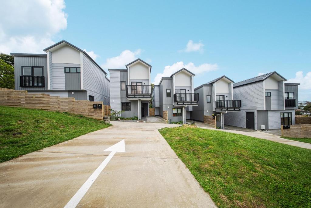 a row of houses with an arrow on a driveway at West Harbour Modern 4-Bedroom Retreat in Auckland
