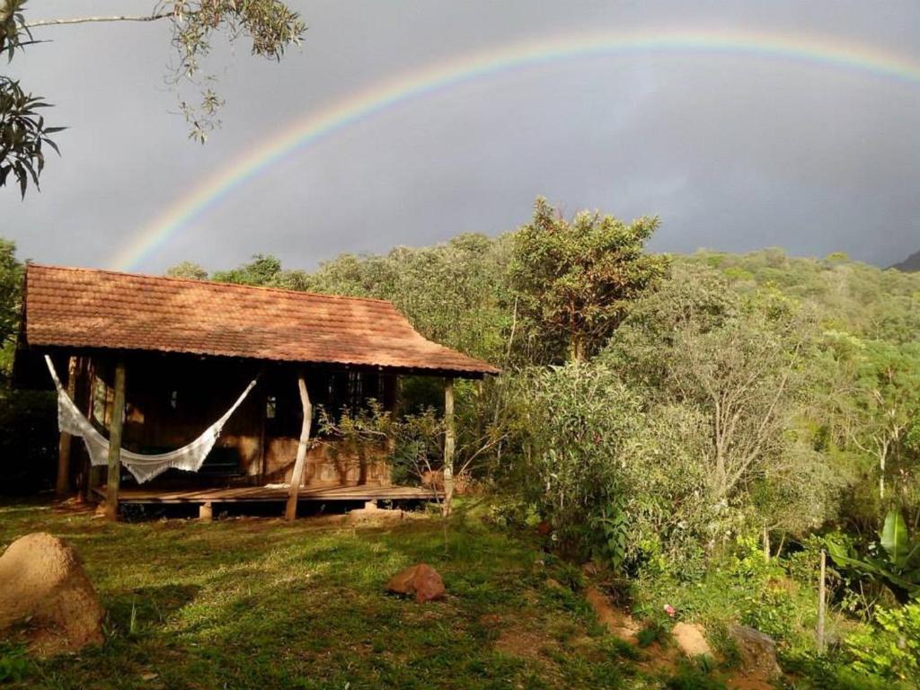 um arco-íris no céu sobre uma casa com uma tenda em Chalé Candeia no Matutu em Aiuruoca