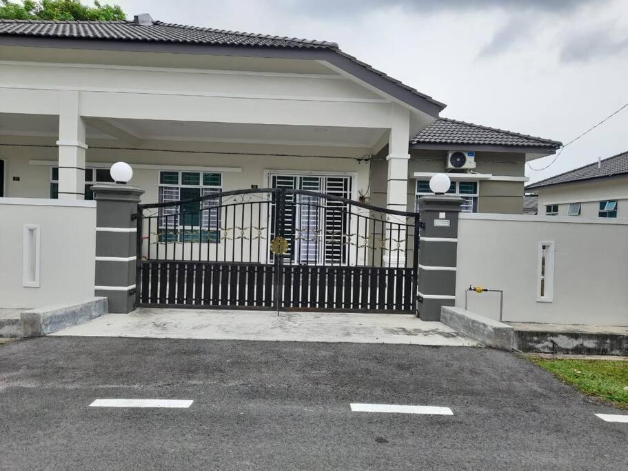 a house with a black gate and a driveway at Sri Keroma Bajandoh Muar Homestay in Muar