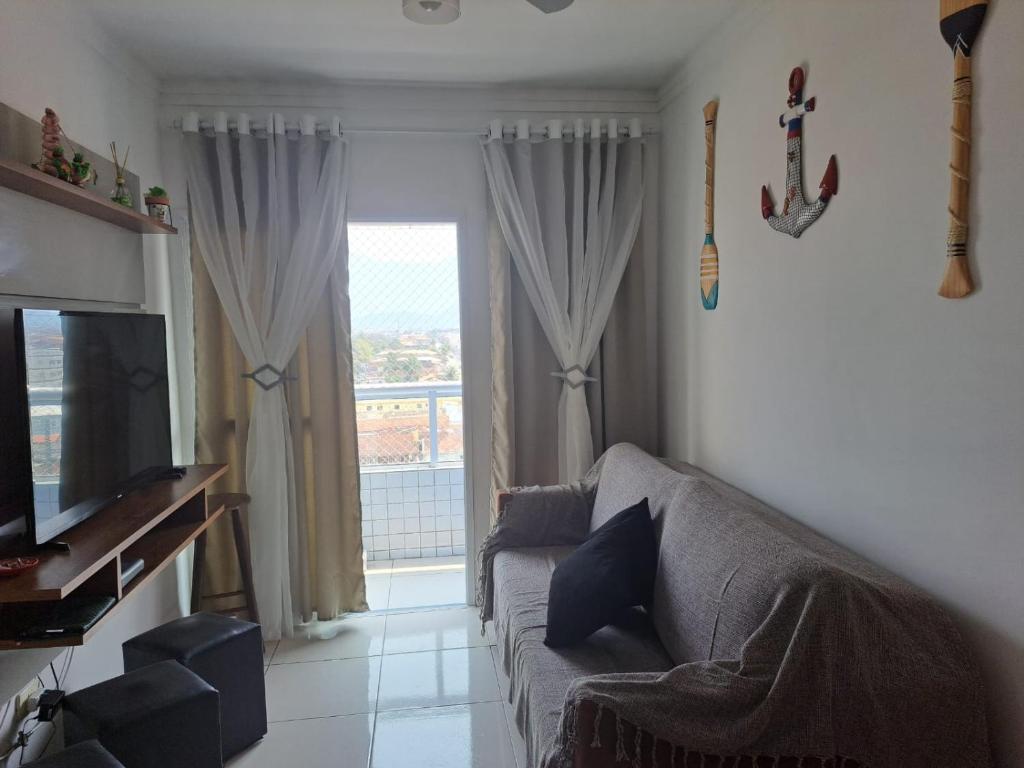 a living room with a couch and a large window at Apto aconchegante beira mar com ar no quarto in Solemar