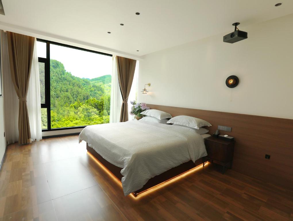 a bedroom with a large bed with a large window at 张家界喜屋民宿 in Zhangjiajie