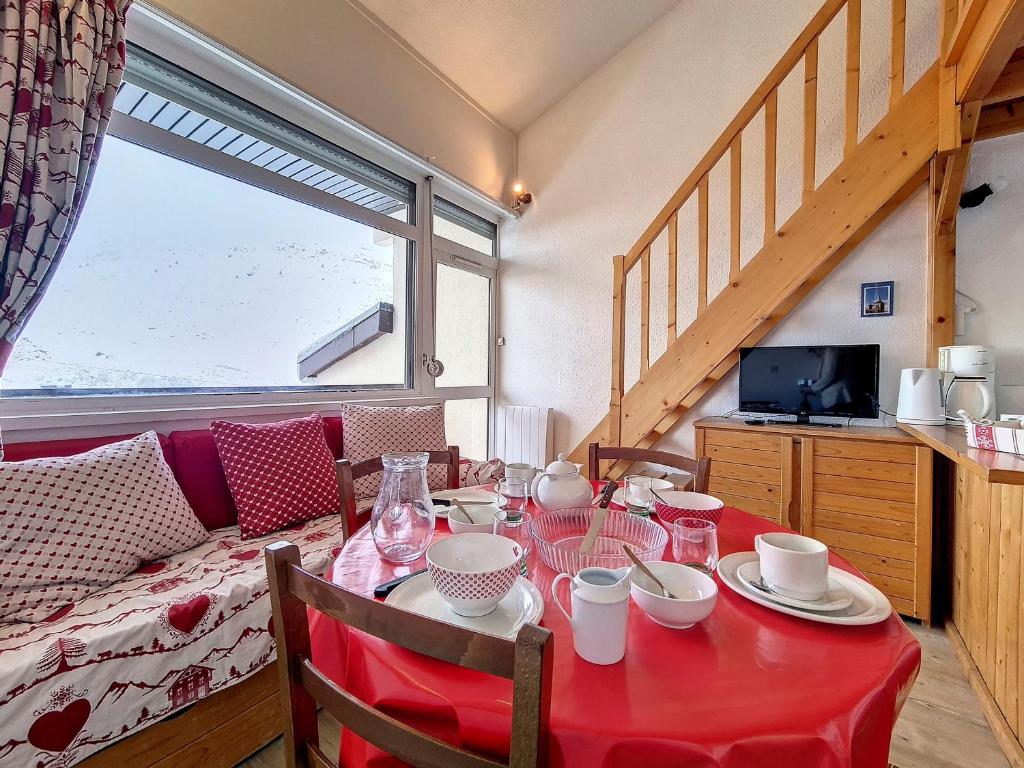 - une table à manger avec une nappe rouge dans l'établissement Appartement cosy · Proche pistes · Balcon · Parking privé - FR-1-344-1199, aux Menuires