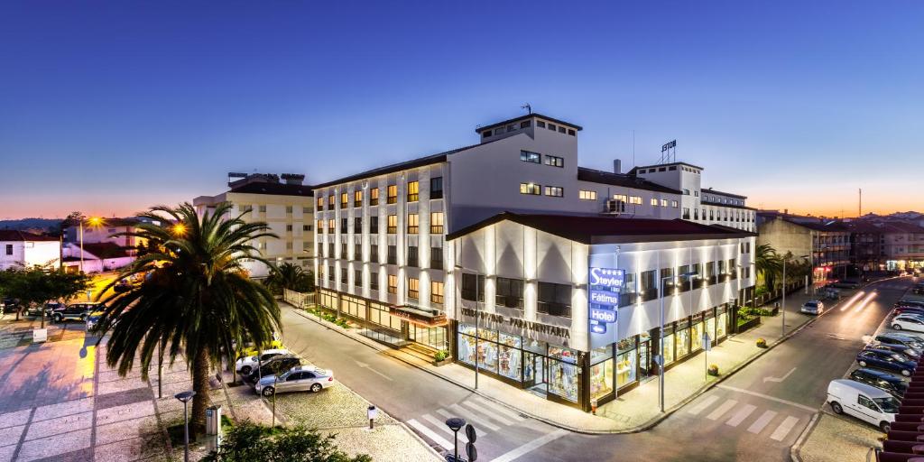 un gran edificio en una calle de la ciudad con aparcamiento en Steyler Fatima Hotel & Congress en Fátima