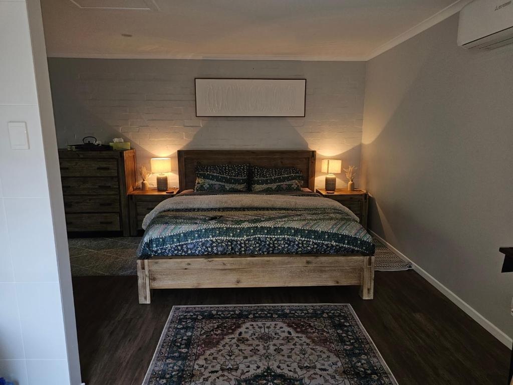 The Garden House BnB في Barellan Point: غرفة نوم بها سرير وطاولتين جانبيتين ومصباحين