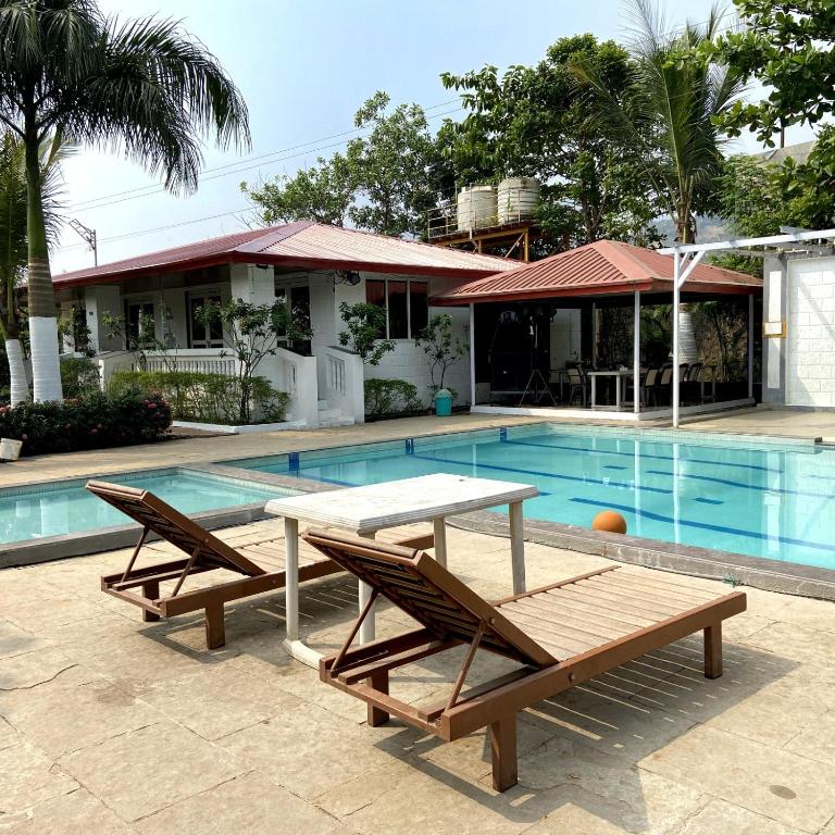 a pool with two benches and a table next to a house at pra tiksha farm in Karjat