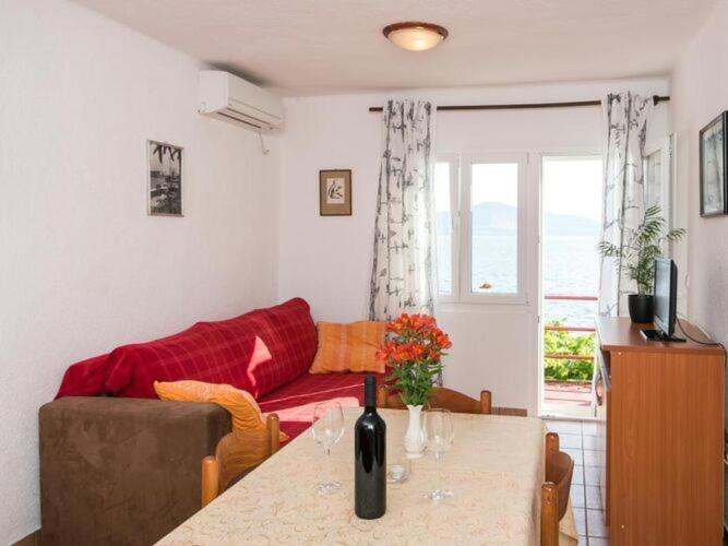 ein Wohnzimmer mit einem Tisch und einer roten Couch in der Unterkunft Apartments Stipo - Comfort Two Bedroom Apartment with Balcony and Sea View A2 in Drače
