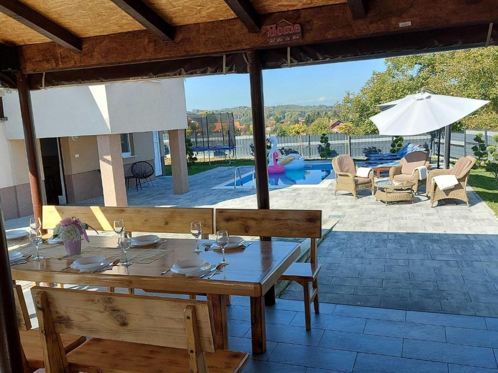 a wooden table with chairs and a patio with a pool at Holiday Home Gra ec - Three Bedroom Holiday Home with swimming pool in Zagreb