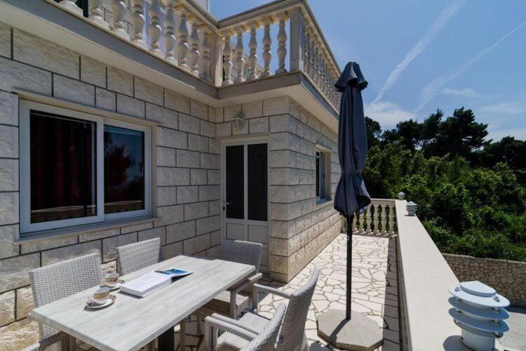 un patio avec une table et un parasol dans l'établissement Apartments Villa Dinga -Borak - Comfort Two Bedroom Apartment with Balcony No 6, à Potomje