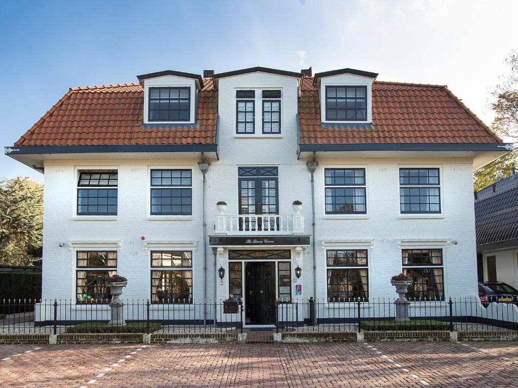 een wit huis met een rood dak bij B & B Hotel The Baron Crown in Den Helder