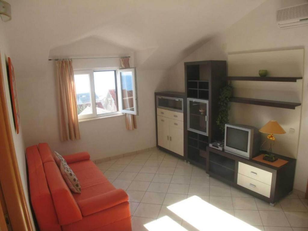 a living room with an orange couch and a television at Apartment in Bol with balcony in Bol