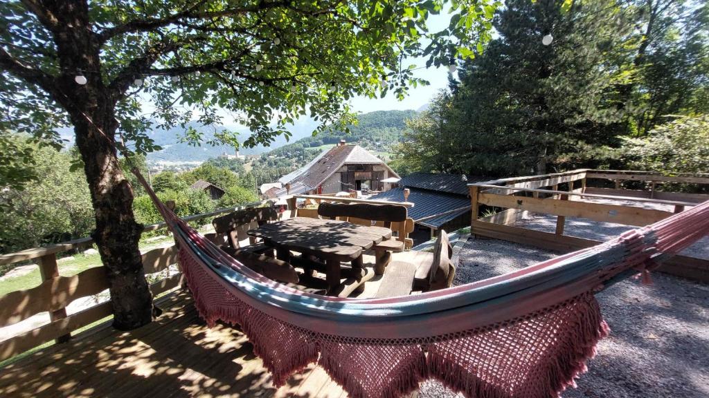 a hammock in a yard with a tree and a house at Yourtes Olachat proche Annecy in Faverges