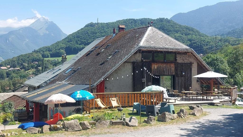 a building with chairs and umbrellas in front of it at Yourtes Olachat proche Annecy in Faverges