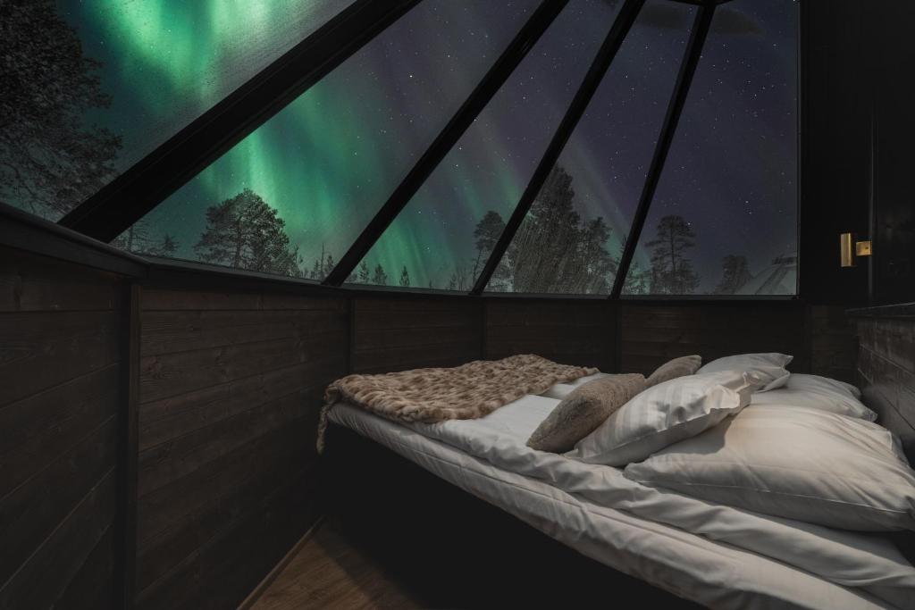 a bed in a room with a view of the northern lights at Wilderness Hotel Nellim & Igloos in Inari