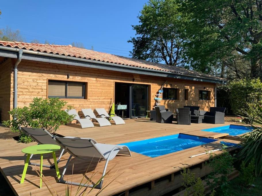 une arrière-cour avec une piscine, des chaises et une maison dans l'établissement Casa Lenha, Maison en bois avec 2 bassins, à Soustons