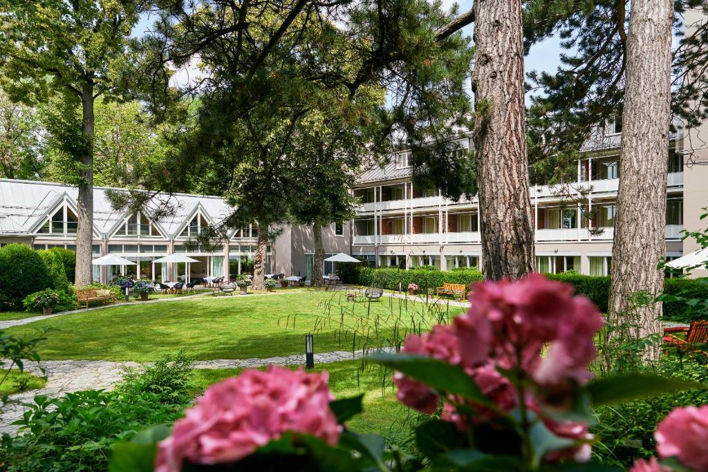an exterior view of a building with pink flowers at Parkhotel Rothof in Munich