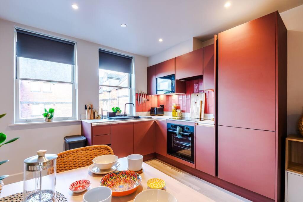a kitchen with red cabinets and a table with food on it at Luxury 2B City Centre Apartment with Private Parking in Chester