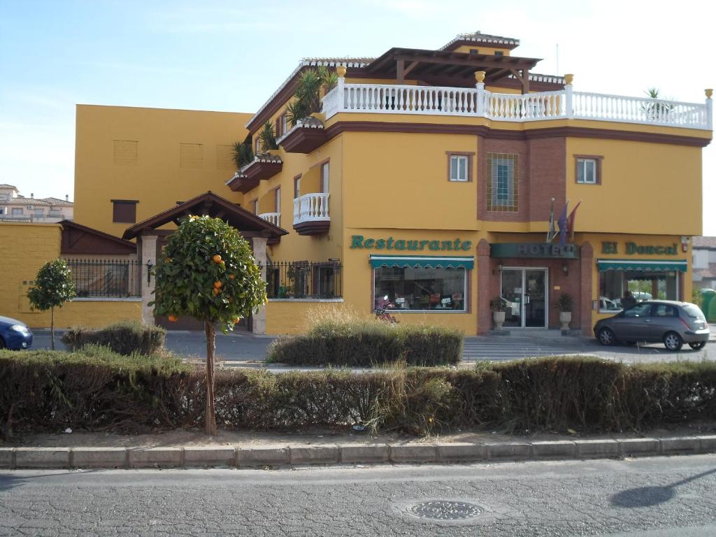 un bâtiment jaune avec un arbre devant lui dans l'établissement Hotel El Doncel, à Atarfe