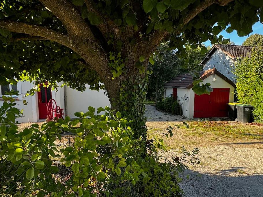 Ein Baum vor einem Haus mit einer roten Garage in der Unterkunft Villa Beauséjour in Saint-Hilaire-Saint-Mesmin