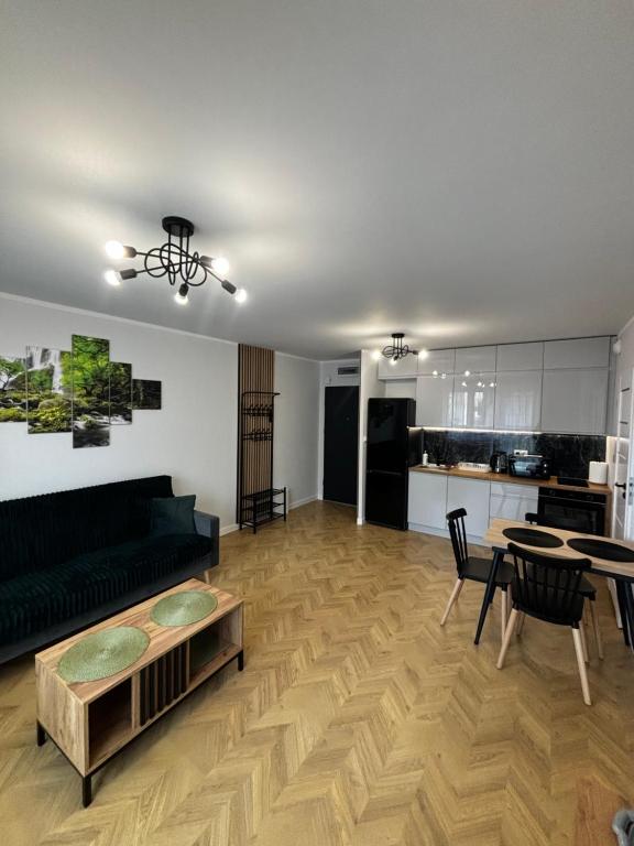a living room with a black couch and a table at Apartament Podolszyce 14 in Płock