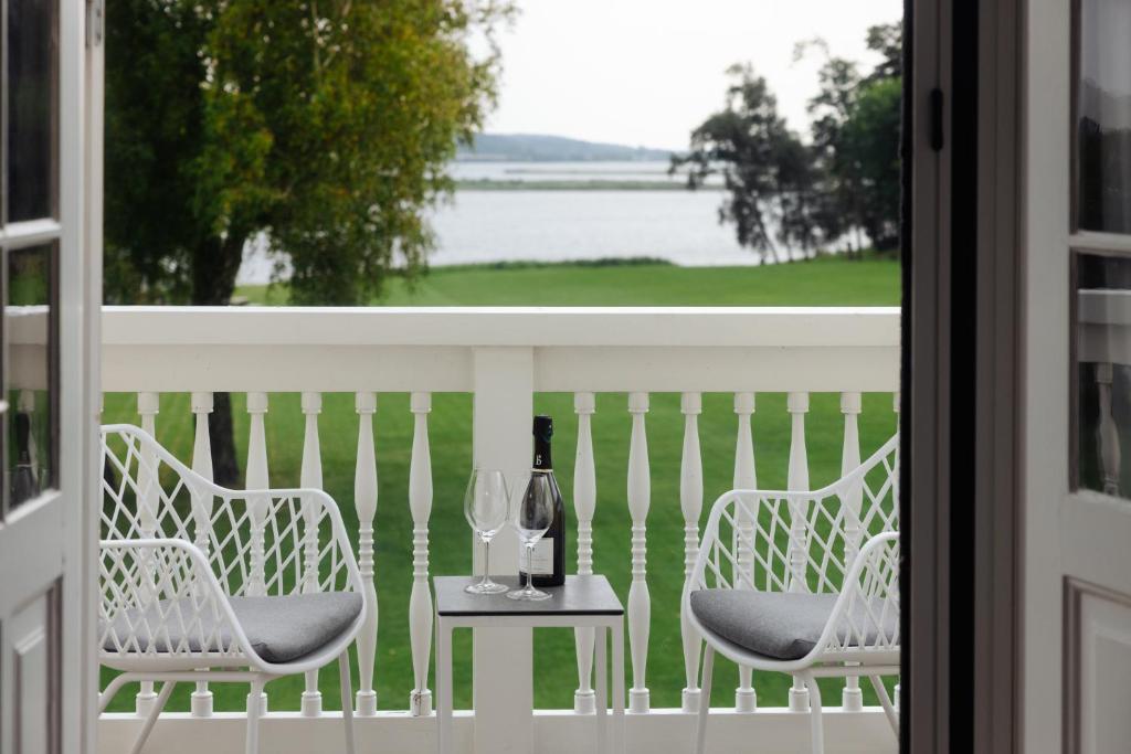 a table with two chairs and a bottle of wine on a balcony at Gl. Avernæs Sinatur Hotel & Konference in Ebberup