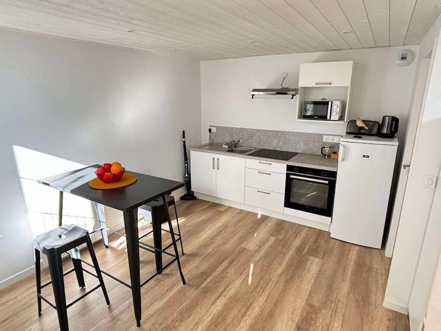 une cuisine avec une table avec un bol de fruits dessus dans l'établissement L'Hirondelle, studio rénové au coeur d'Arago, à Les Sables-dʼOlonne