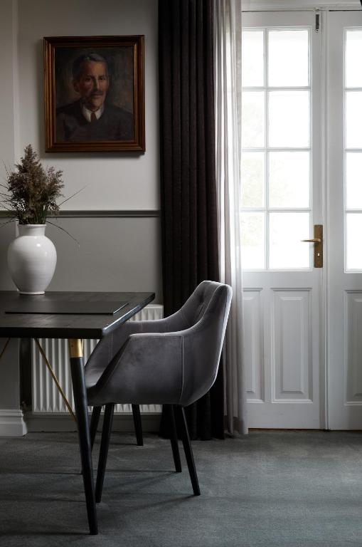 a table with a chair and a portrait of a man at Gl. Avernæs Sinatur Hotel & Konference in Ebberup