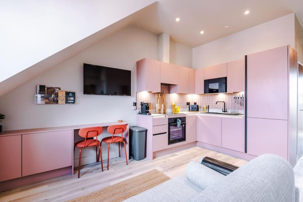a kitchen with pink cabinets and red bar stools at City Centre Apartment Free Parking and Luxury Finishes in Chester