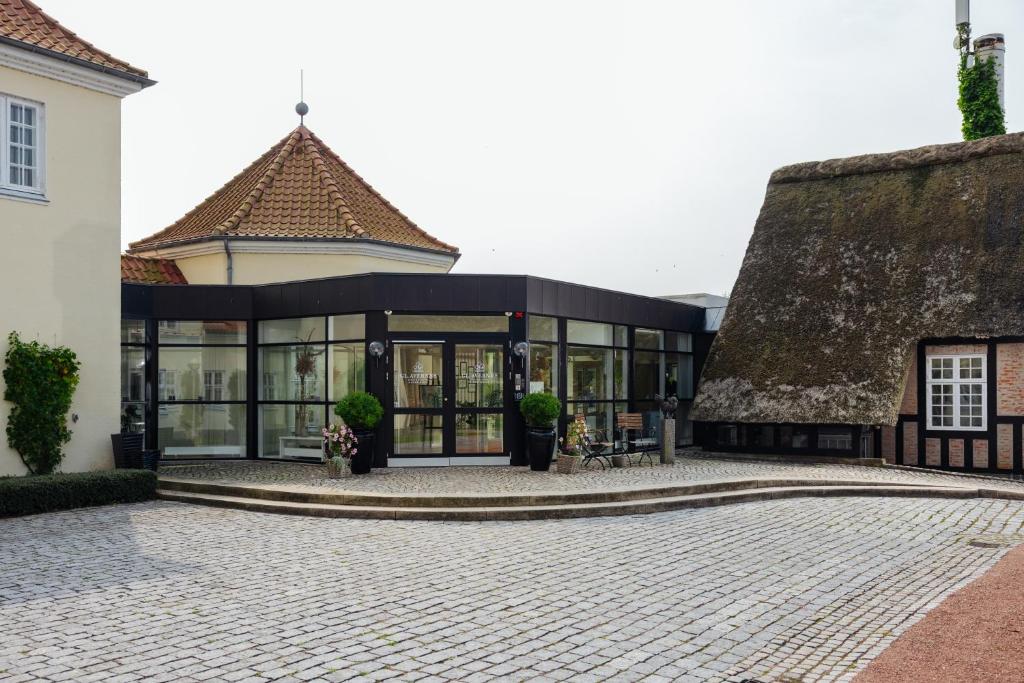 a building with a thatched roof and a courtyard at Gl. Avernæs Sinatur Hotel & Konference in Ebberup