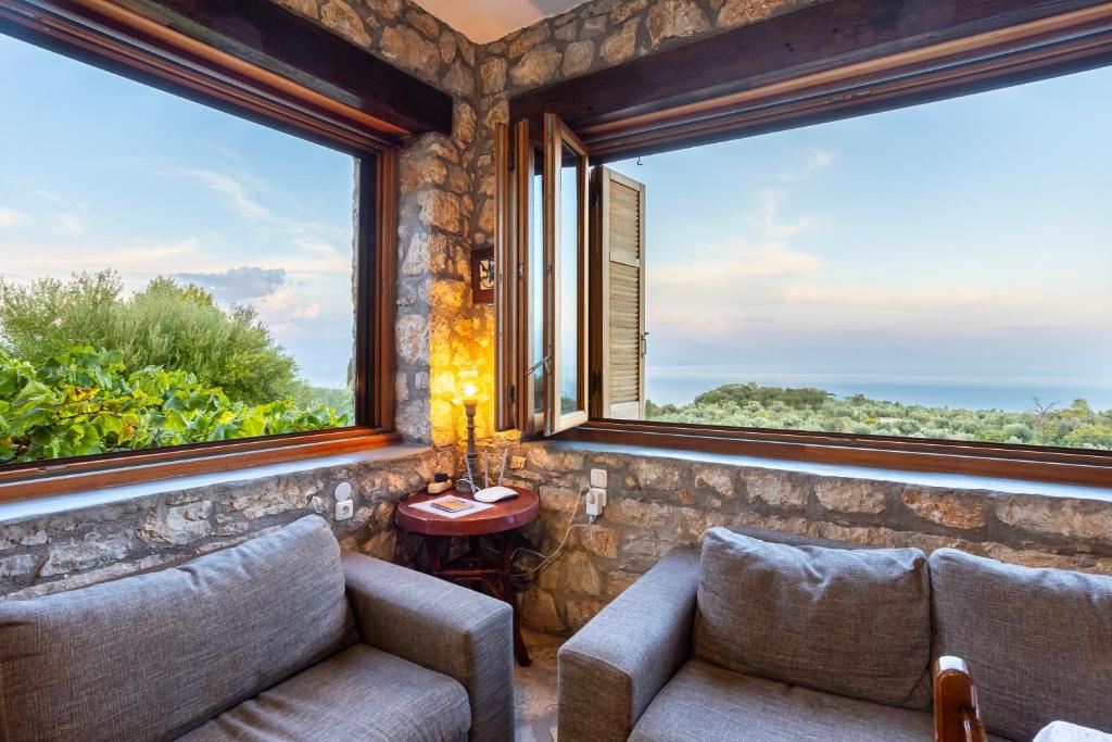 a living room with two couches and large windows at Stone Farmhouse in Groves - Sea & Mountain Views in Kalamaki Messinia
