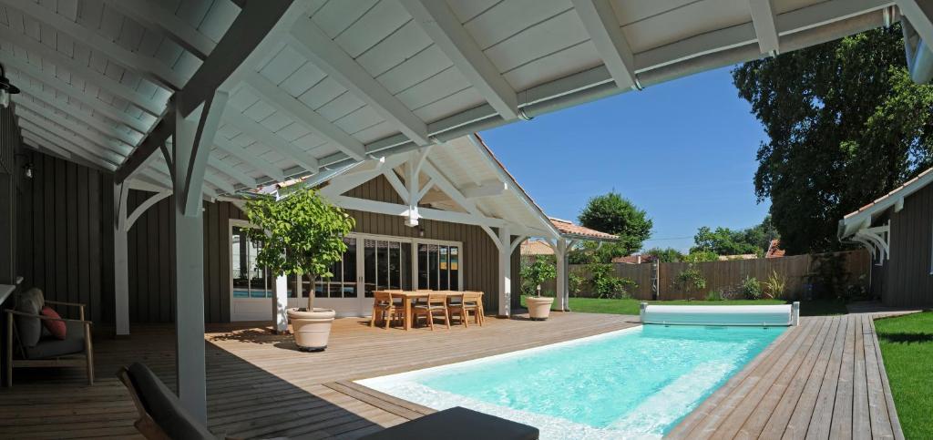 a patio with a swimming pool and a pergola at La villa aux oiseaux in Andernos-les-Bains