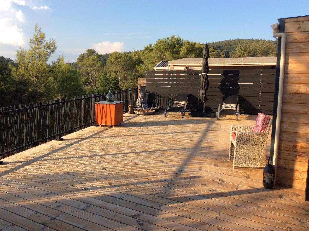 une grande terrasse en bois avec des chaises et un coin salon. dans l'établissement Mon petit coin de paradis, à Rocbaron