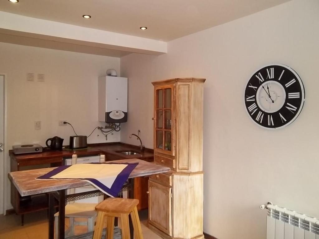 a kitchen with a clock on the wall and a table at Aparts de los Pajaros in El Calafate