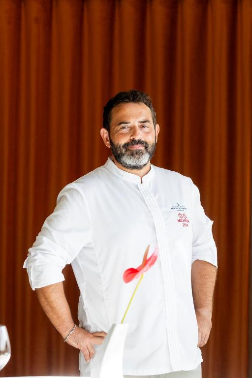 a man in a white shirt with a flower on his shirt at Grand Hotel Principe Di Piemonte in Viareggio