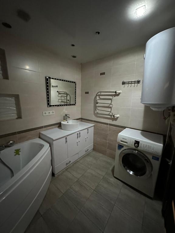 een badkamer met een wasmachine en een wastafel bij 2 ком люкс в центре города in Karagandy