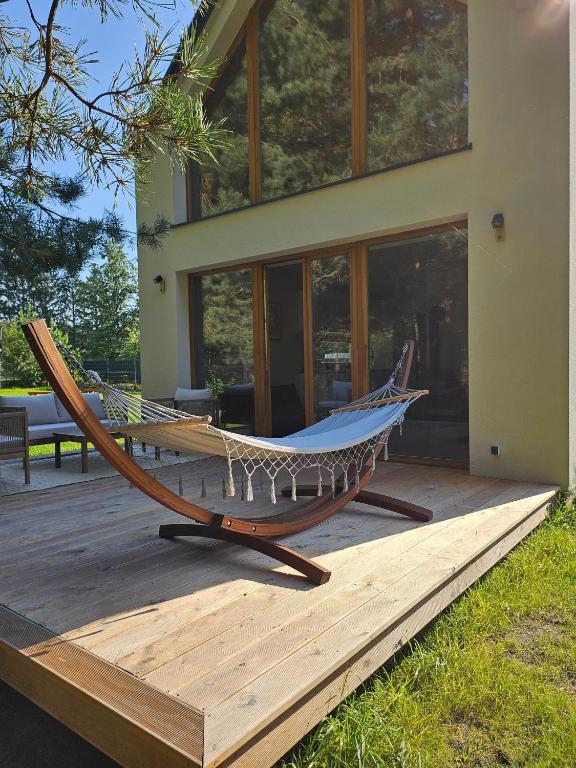 a hammock on a deck in front of a house at Domek w Lesie z Kominkiem i Ogrodem Niedalino in Niedalino