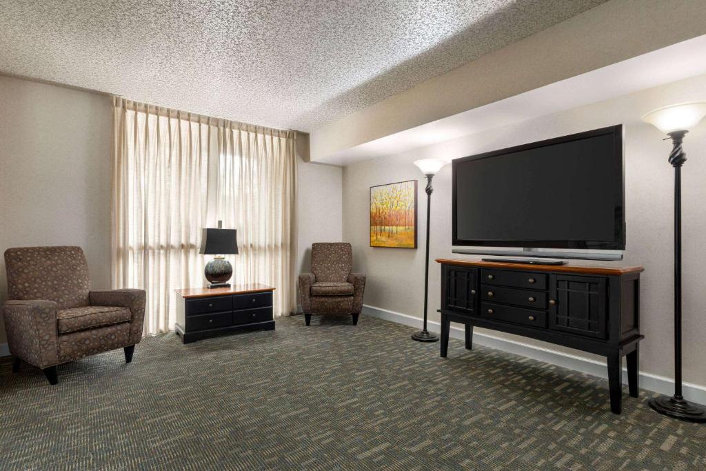 een hotelkamer met een flatscreen-tv en stoelen bij Hotel Barkley in Kuttawa