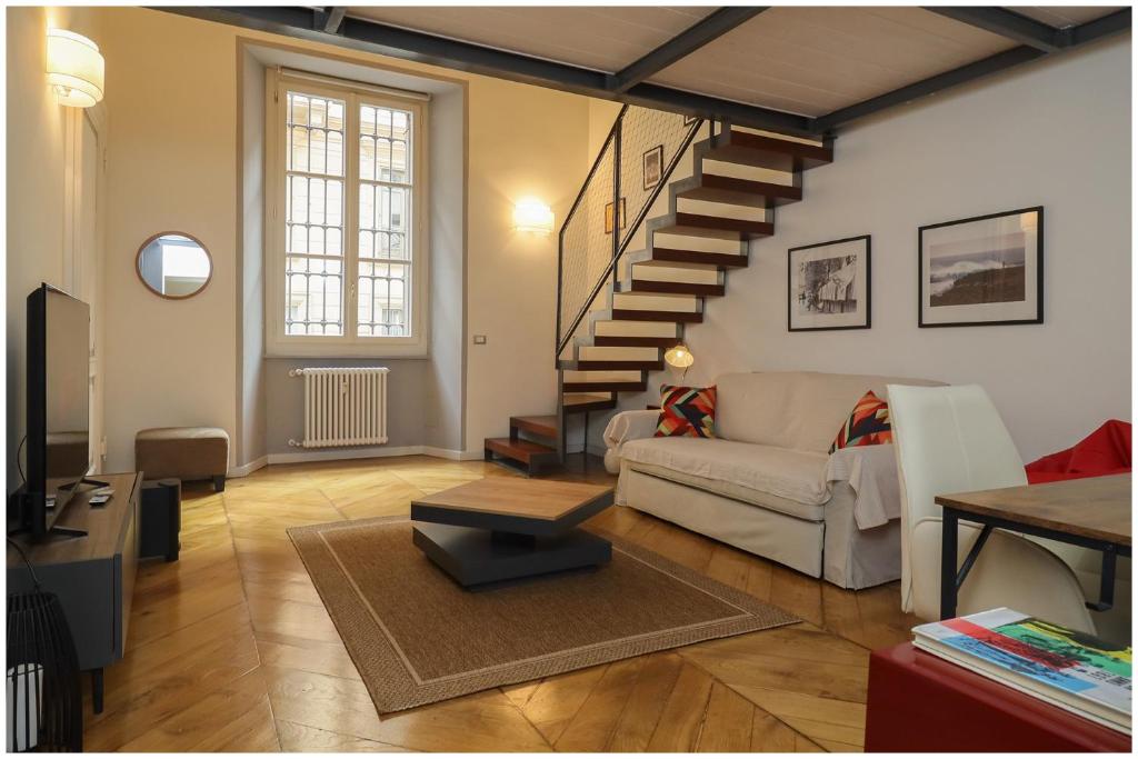Una sala de estar con un sofá y una escalera. en L'oasi in piazza Bodoni, en Turín
