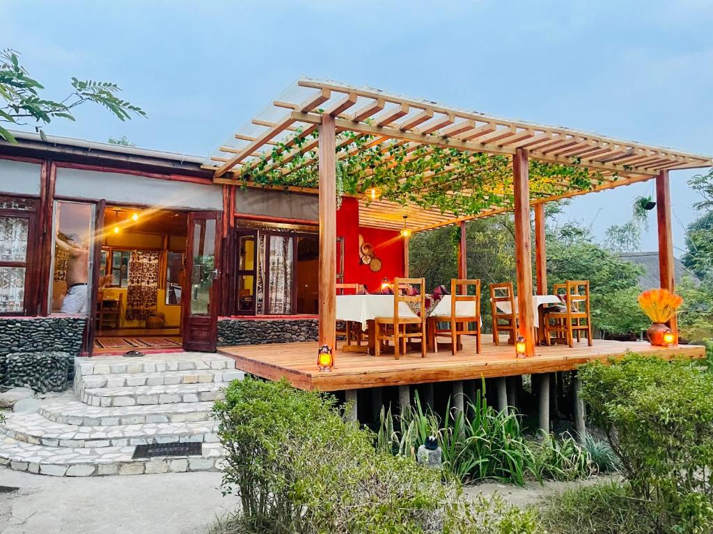 a house with a wooden deck with tables and chairs at Wild Tracks Overland Camp in Kasese