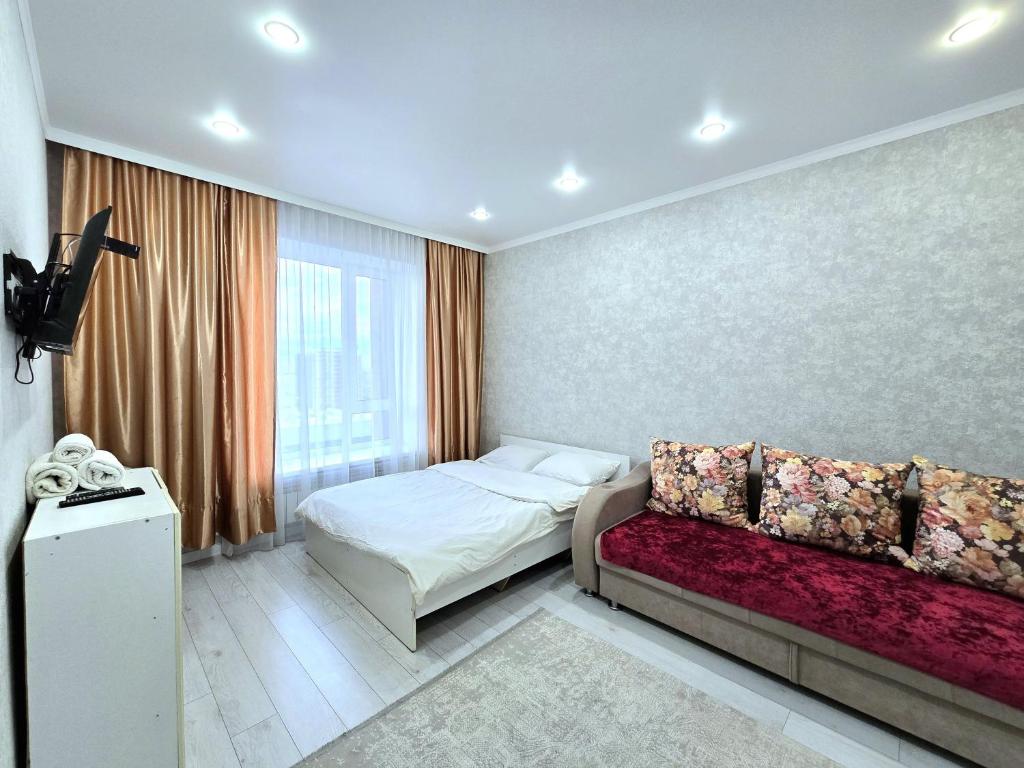 een kleine slaapkamer met een bed en een bank bij Аэропорт 10 минут жк Будапешт163 in Astana