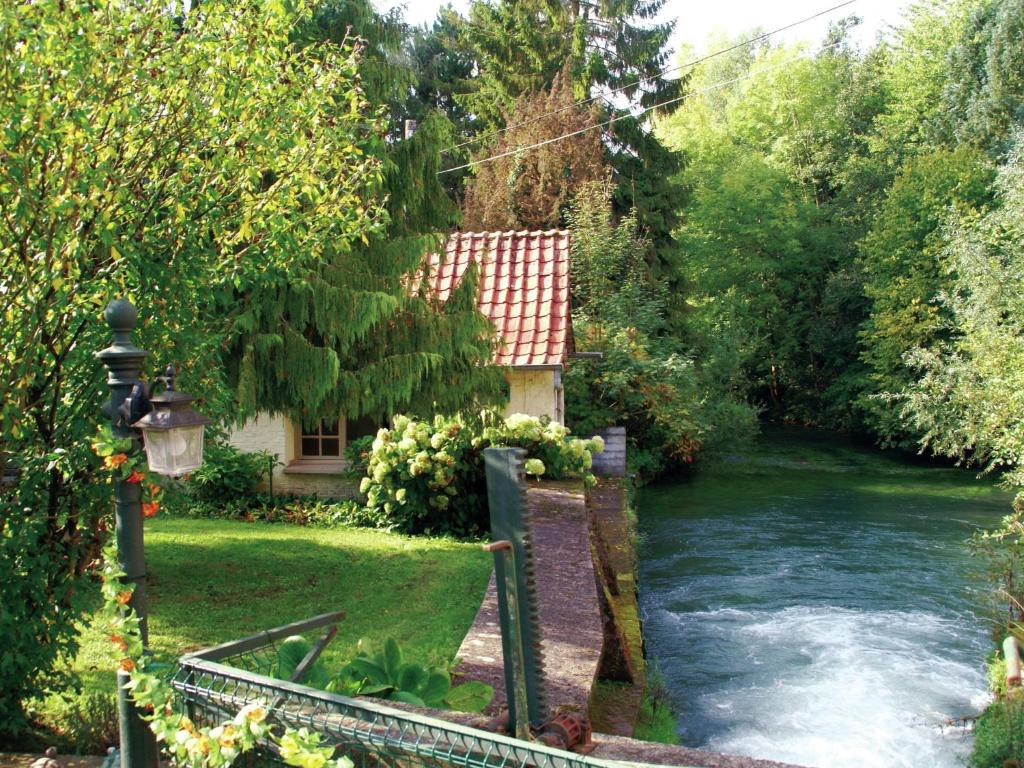 a house next to a river in a yard at Cottage near the Mill Pond with a beautiful garden in Le Ponchel