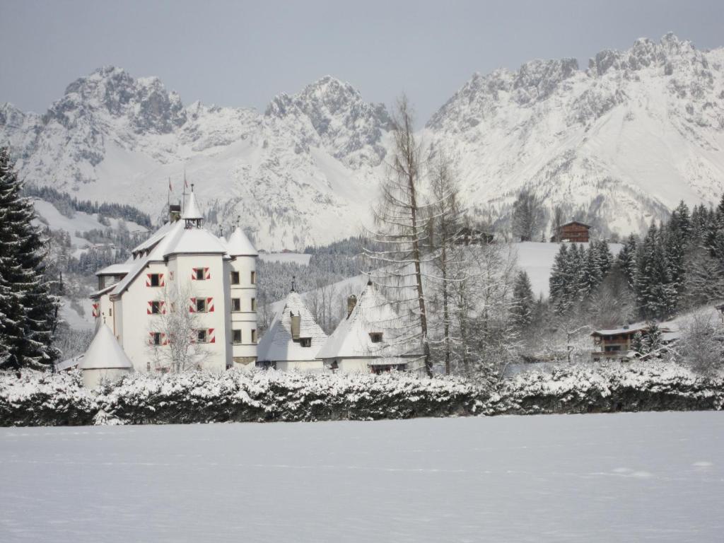 een gebouw in de sneeuw naast een waterlichaam bij Schloss Münichau in Reith bei Kitzbühel