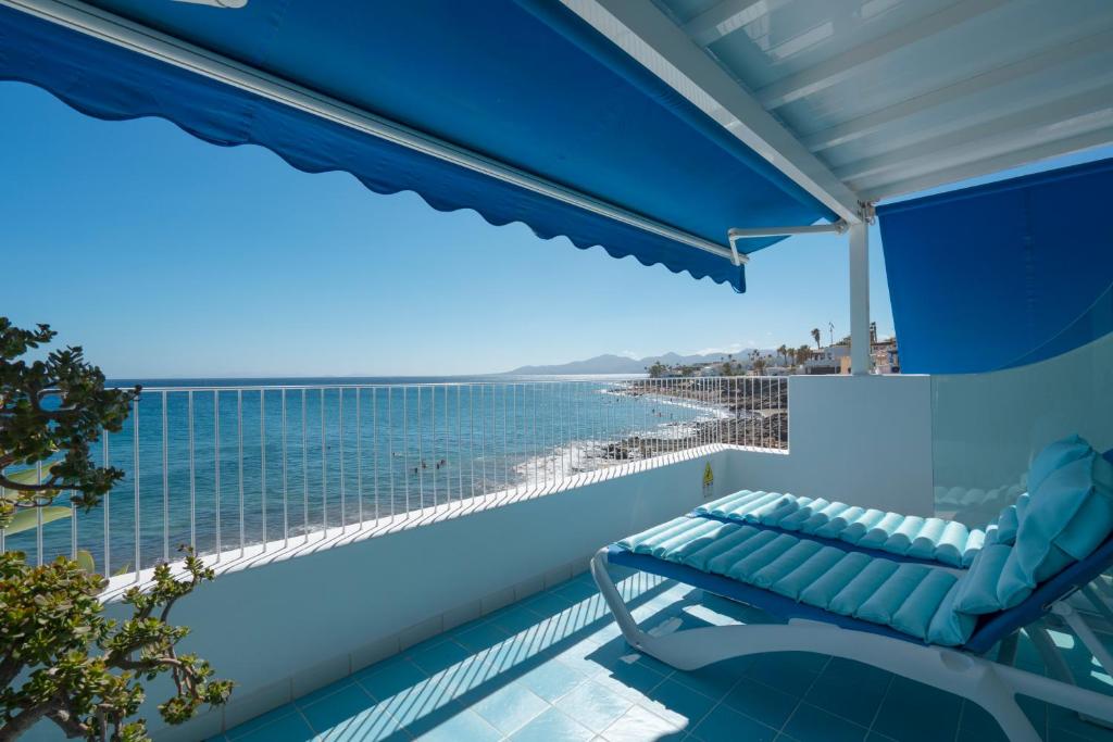 a chair on a balcony with a view of the ocean at Sea Front Caletón Suite in Los Pocillos