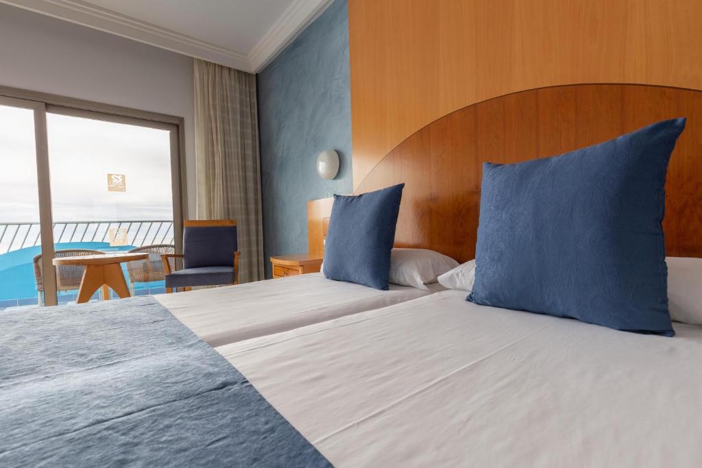 a hotel room with two beds with blue pillows at R2 Hotel Pajara Beach in Costa Calma