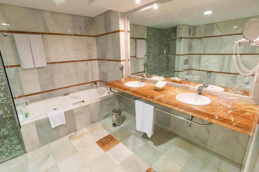 a bathroom with two sinks and a bath tub at R2 Hotel Pajara Beach in Costa Calma